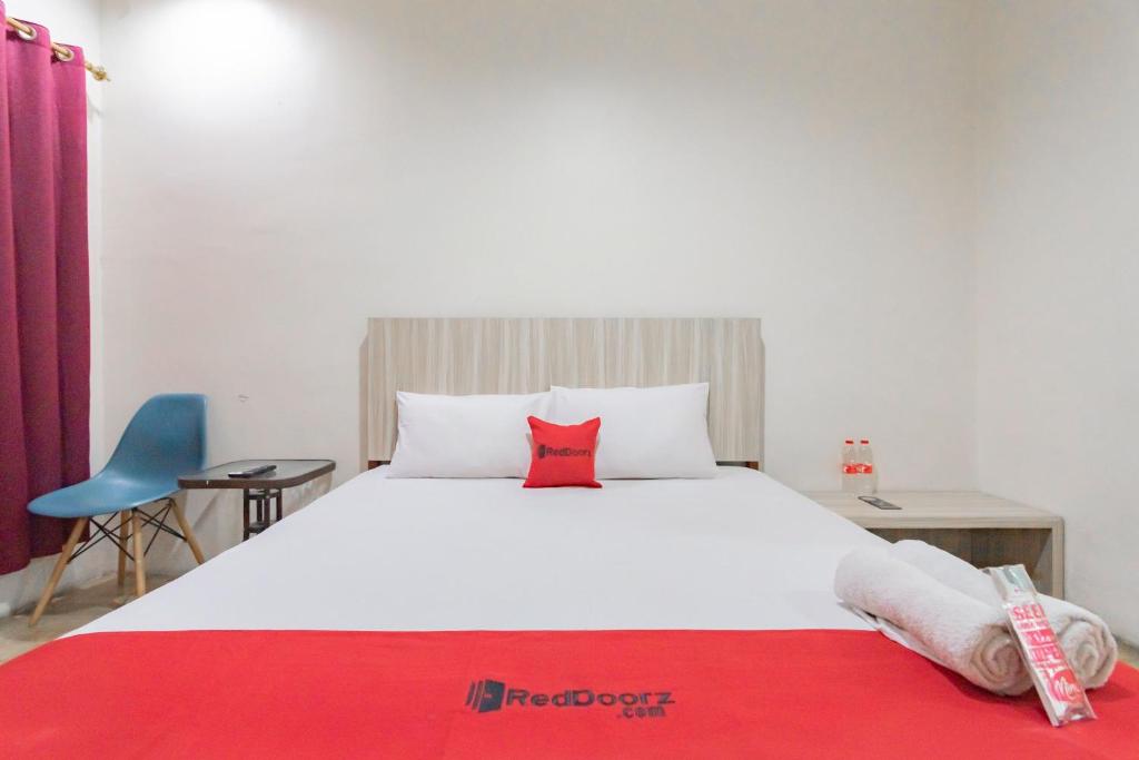 a bedroom with a large white bed with a red pillow at RedDoorz Syariah at Cigadung Raya Street in Bandung