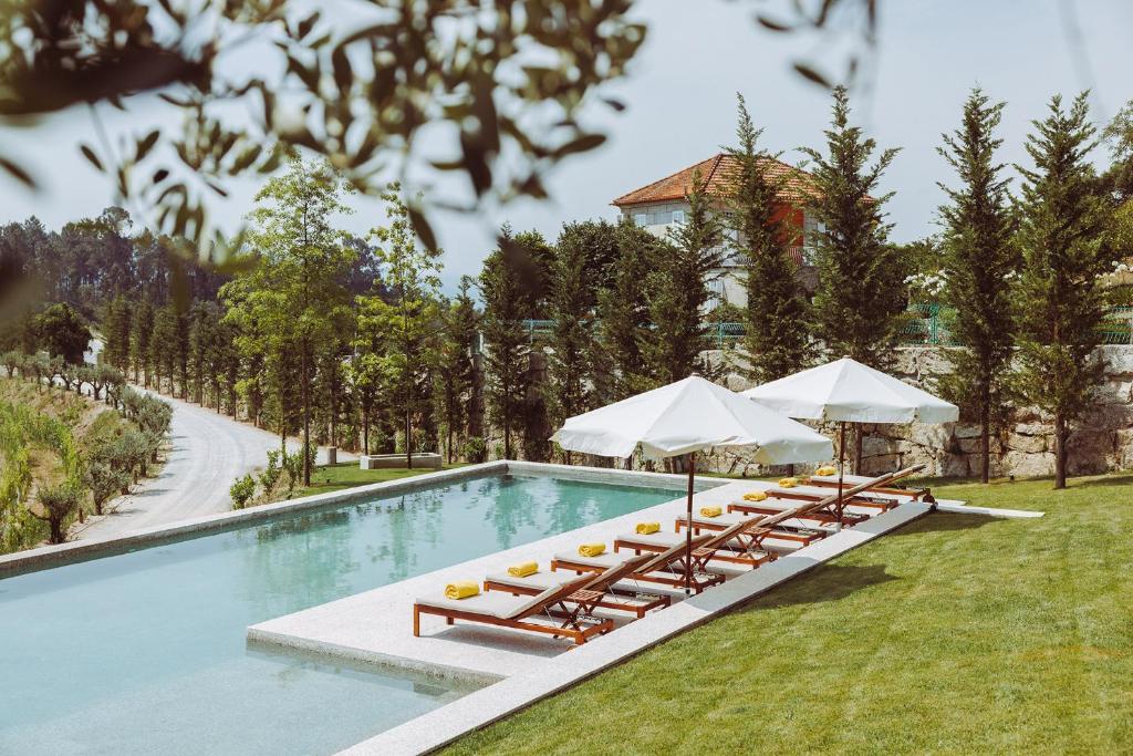 uma piscina com espreguiçadeiras e guarda-sóis em Oliveiras Village — Agroturismo em Amarante