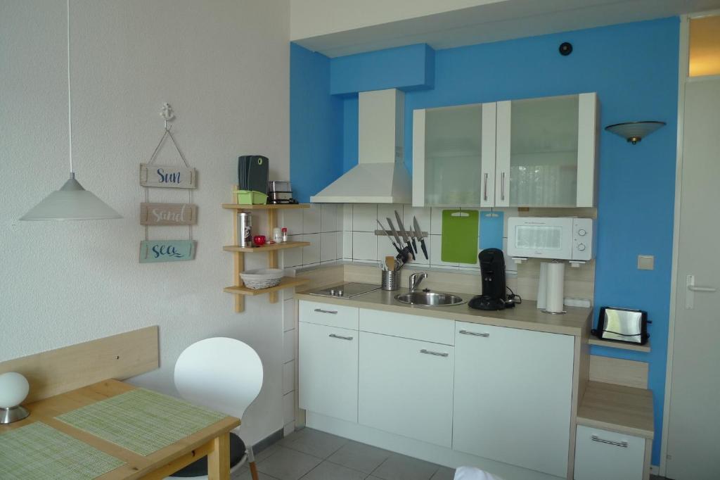 a kitchen with white cabinets and a blue wall at Appartment 530 in Tossens in Tossenserdeich