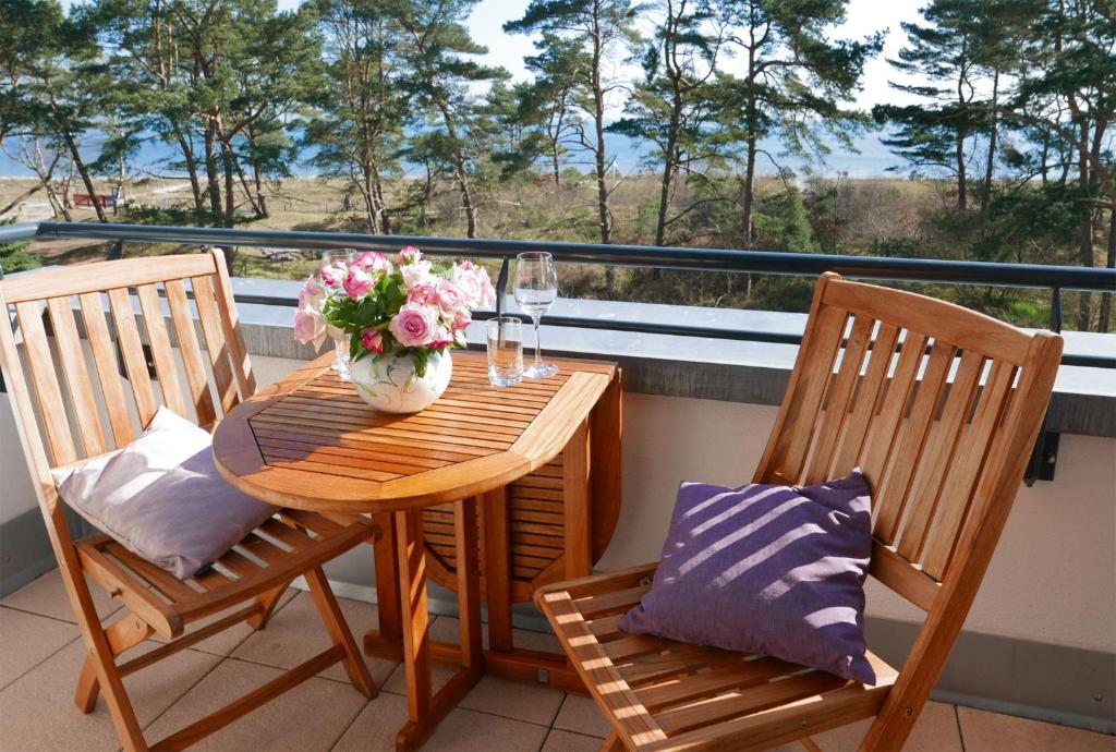 a wooden table with a vase of flowers on a balcony at Haus Meeresblick - Ferienwohnung Meerblick (Ref. 128699) in Baabe