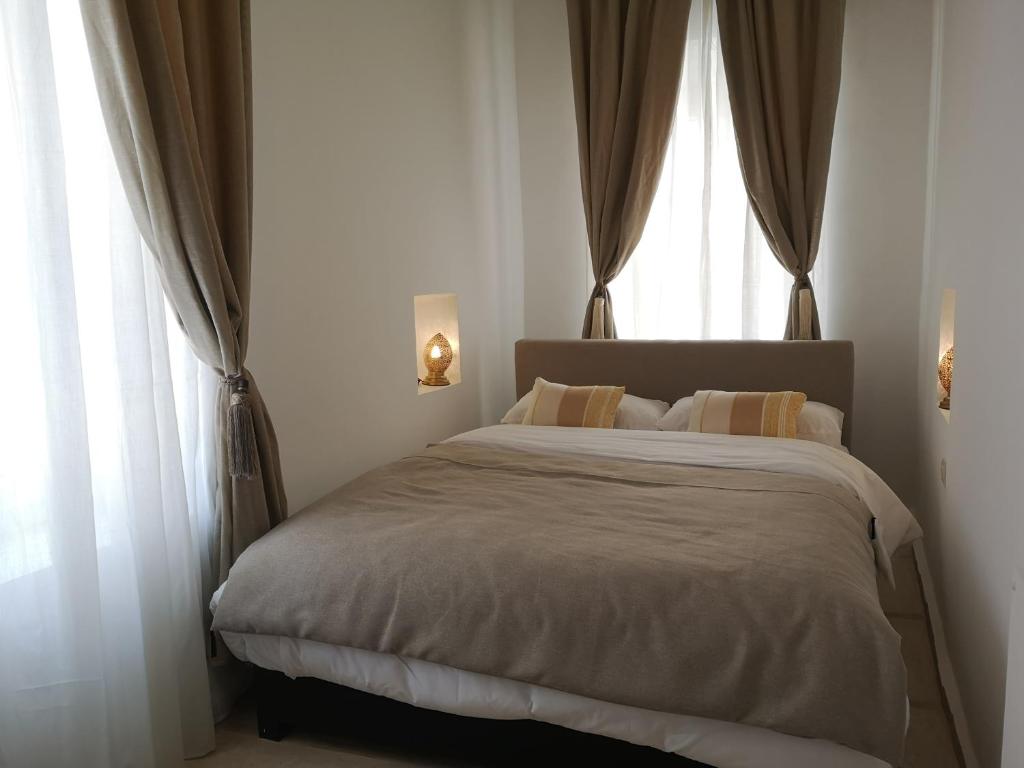 a bedroom with a large bed with two windows at Riad de charme l'Oasis d'Essaouira - Suite Luxe in Essaouira