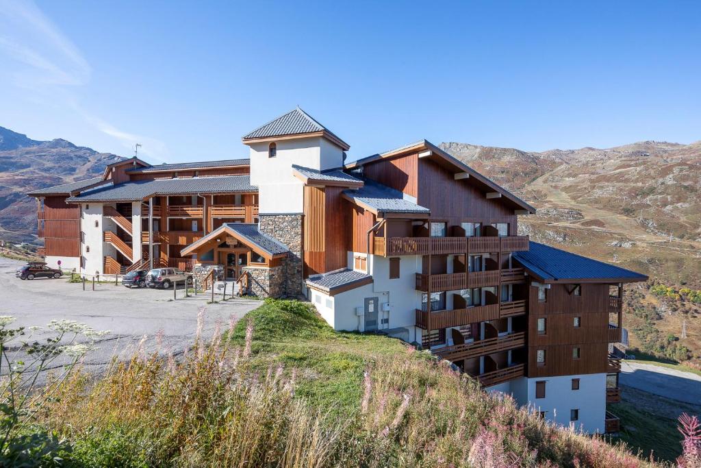 um hotel no topo de uma colina com montanhas ao fundo em Résidence Le Necou - Les Ménuires em Les Menuires