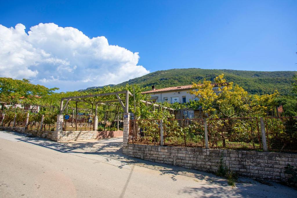 a fence in front of a building with a mountain in the background at Apartment Falichi in Plomin
