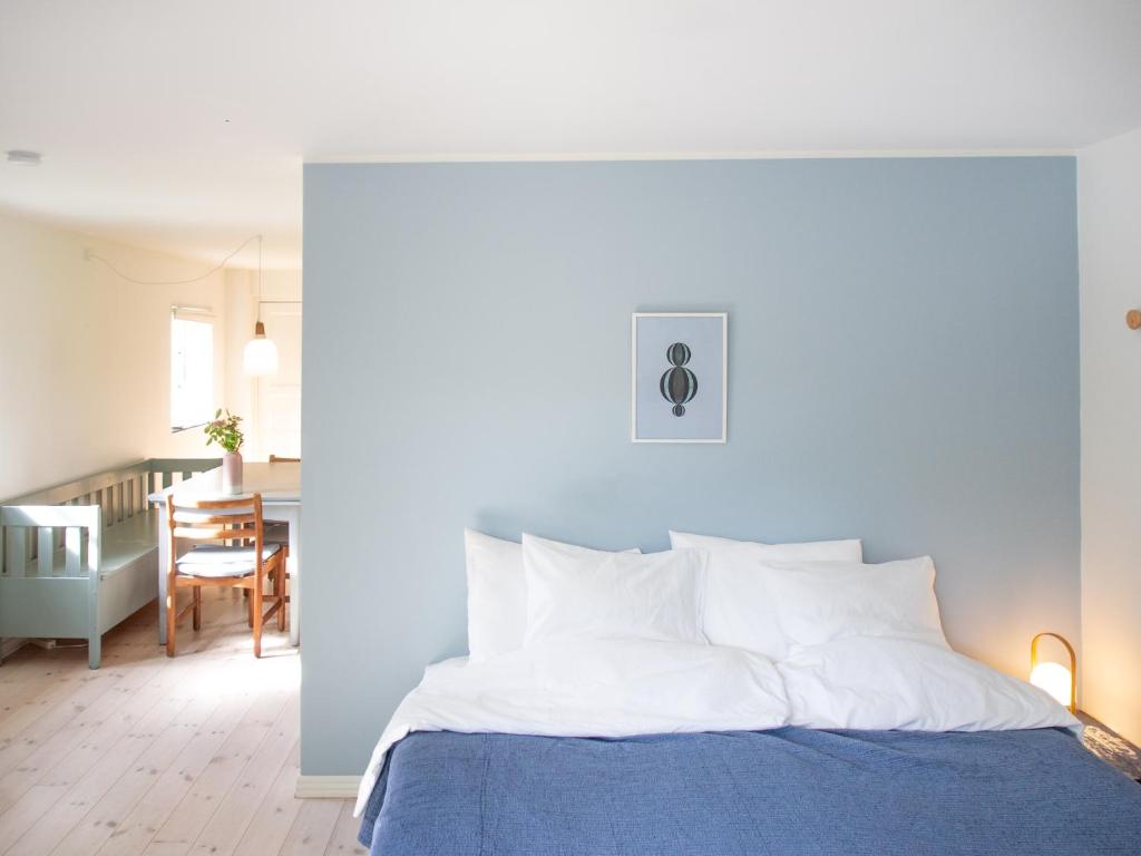 a bedroom with a blue and white bed and a dining room at Kamilla's cottage, 1 km. from the beach in Stege