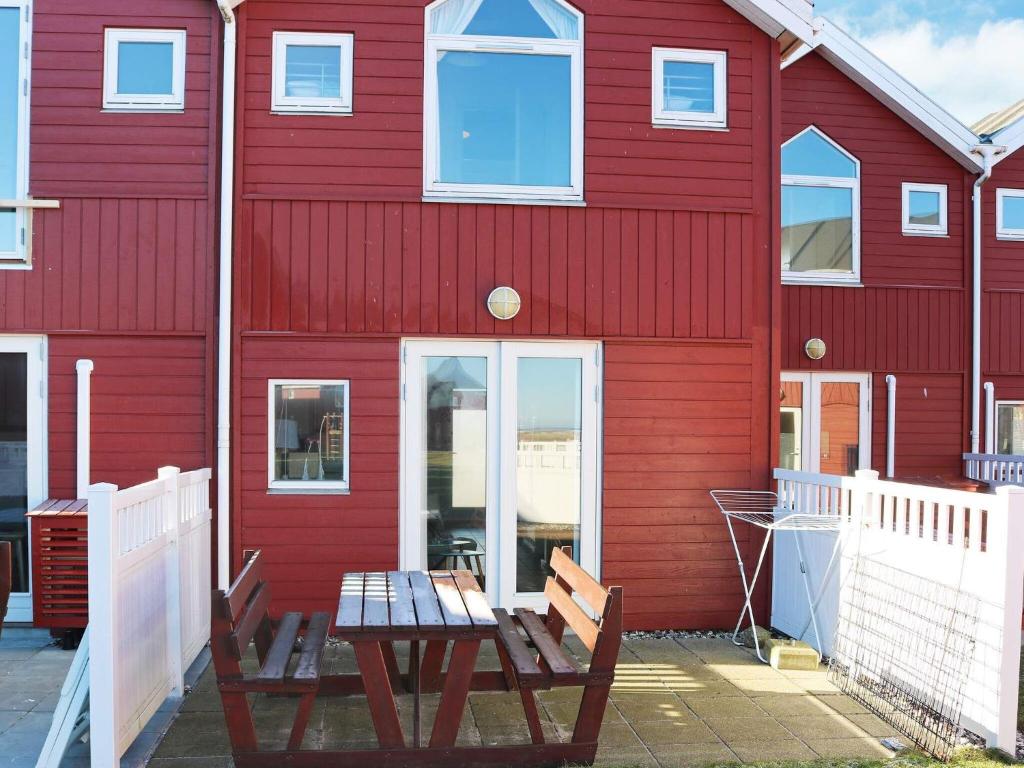 um edifício vermelho com dois bancos à sua frente em 6 person holiday home in Hadsund em Hadsund