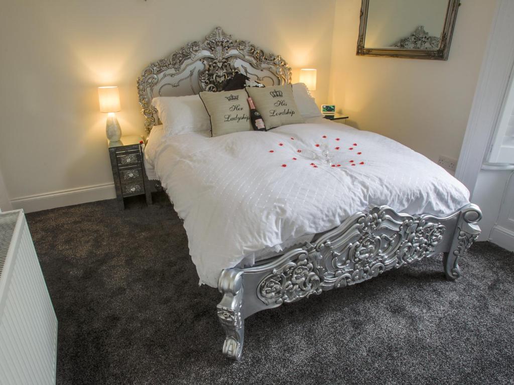 Schlafzimmer mit einem silbernen Bett mit weißer Bettwäsche und Kissen in der Unterkunft Ugthorpe Lodge Hotel in Whitby