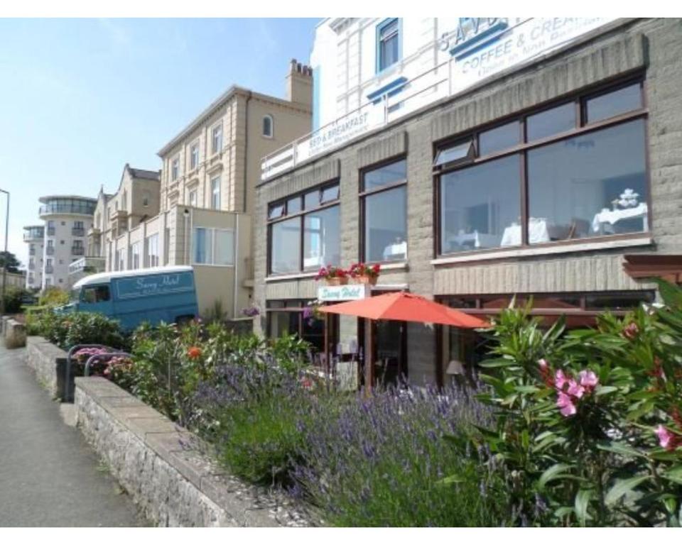 un edificio con un paraguas y flores delante de él en Savoy B&B, en Weston-super-Mare