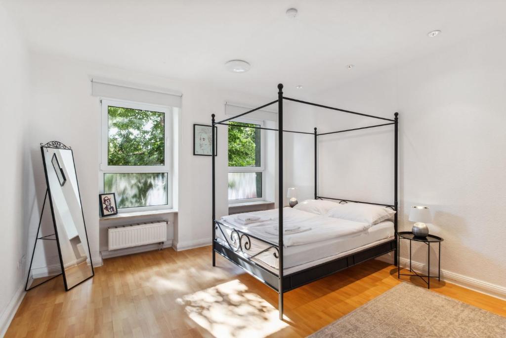 a bedroom with a canopy bed and two windows at Bright 3-room apartment near Prenzlauer Berg in Berlin