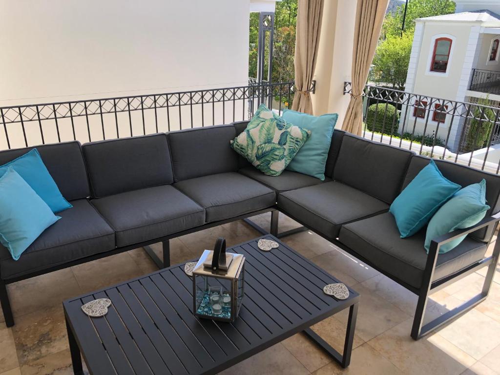 Sofá negro con almohadas azules en el balcón en Apartment Jourdan, en Franschhoek