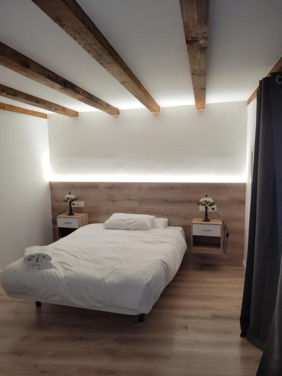 Un dormitorio con una gran cama blanca con dos mesas. en Navarreria, en Pamplona