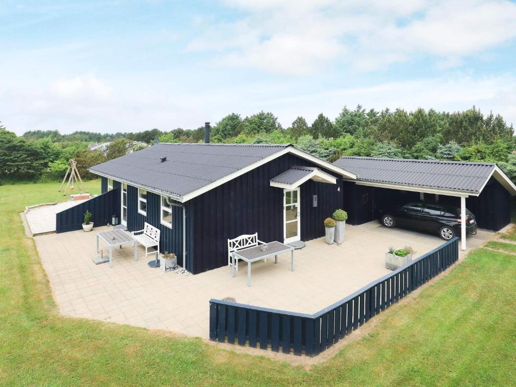 a black shed with a deck and a patio at Holiday home Hjørring IV in Lønstrup