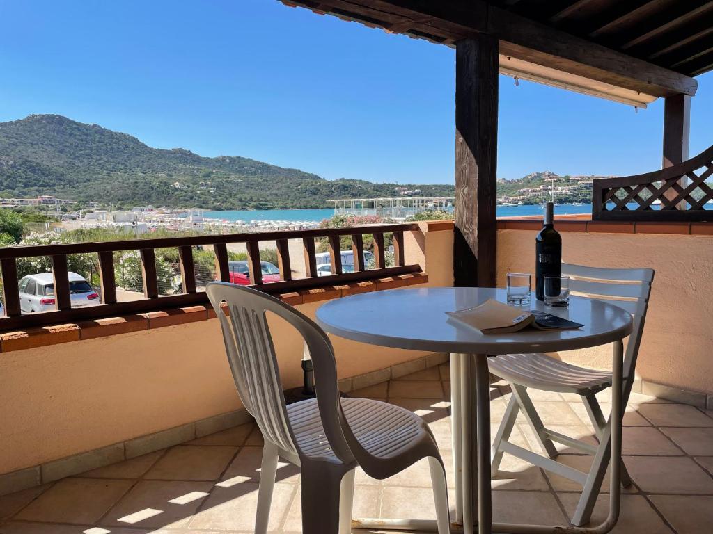 a table and chairs on a balcony with a bottle of wine at Sardegna Beach Cala Reale in Santa Marinella