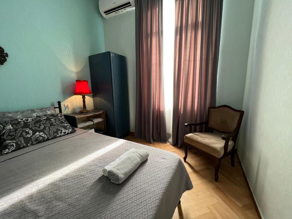 een slaapkamer met een bed, een stoel en een raam bij Lola Apartments in Tbilisi City