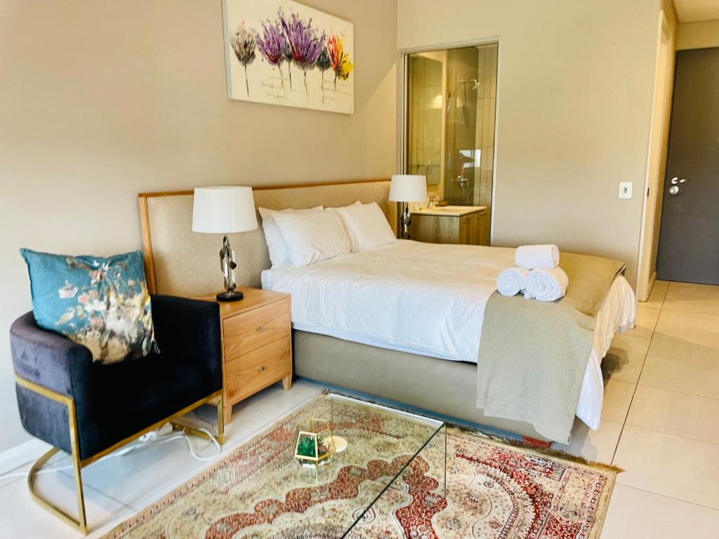 1 dormitorio con 1 cama, 1 silla y 1 mesa en Menlyn Maine Trilogy Hotel, en Pretoria