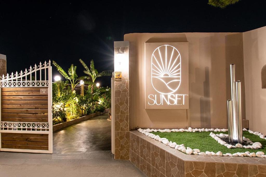 a entrance to a sunset sign at night with a gate at Sunset Apartments Free shuttle from Athen's Airport in Spata