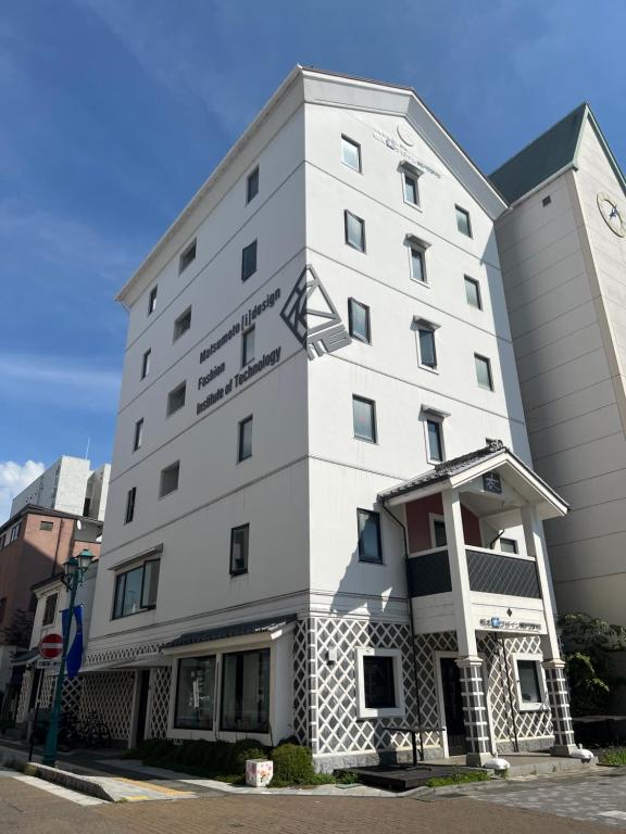 a white building on the corner of a street at Guest House Ichiyama Shukuba in Matsumoto