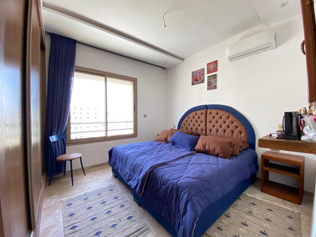 a bedroom with a blue bed and a window at L'APPARTEMENT PARADISIAQUE A HAMMAMET ET NABEUL in Nabeul