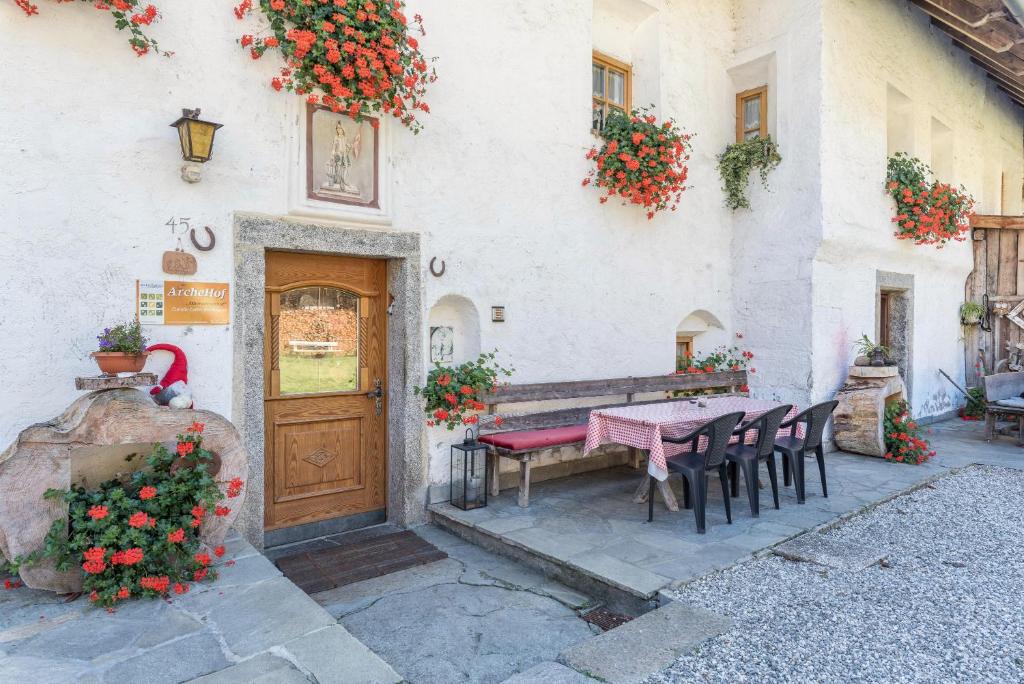 a table and chairs in front of a building with flowers at Oberwieserhof App 1 in San Lorenzo di Sebato