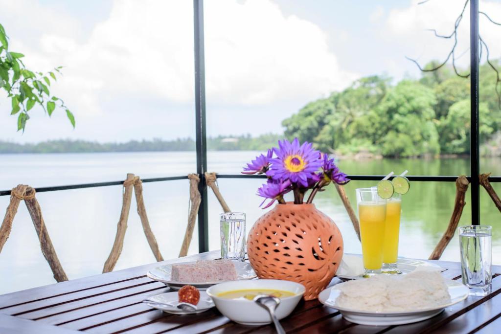 a table with food and a vase of flowers and drinks at Scenery River Star Hotel in Hikkaduwa