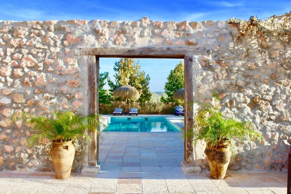 una pared de piedra con una piscina y dos macetas en Room in Villa - Beautiful Accommodation At The Heart Of Andalusia, en Puente Genil