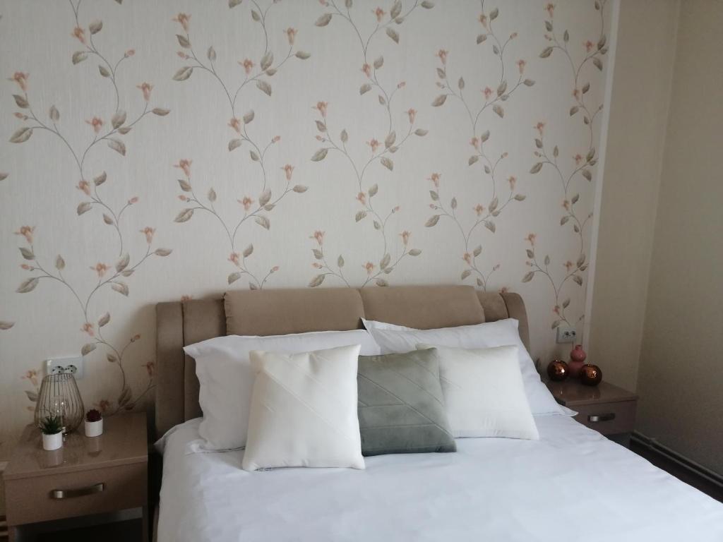 a bedroom with a bed with white sheets and floral wallpaper at Pandora Guest House in Cluj-Napoca