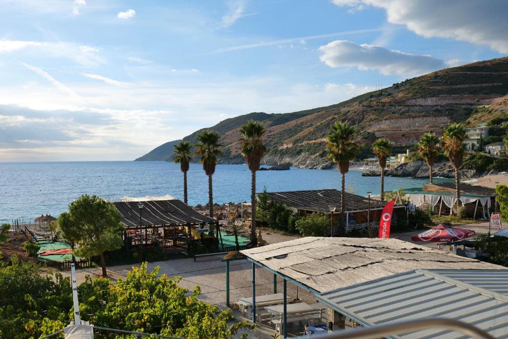 a view of a beach with palm trees and the ocean at Hotel Jali in Himare