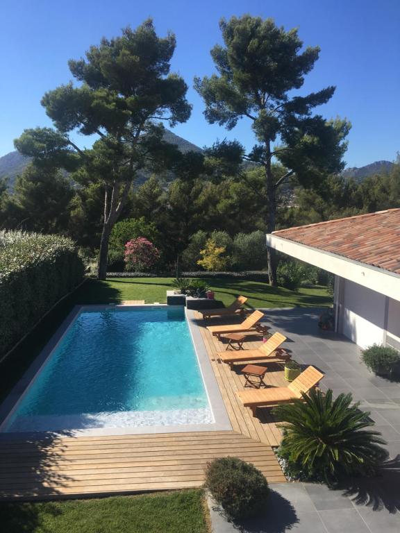 a swimming pool with lounge chairs next to a house at Chambre luxe dans villa de standing avec piscine, accès discret et indépendant, terrasse arborée et parking privé in La Valette-du-Var