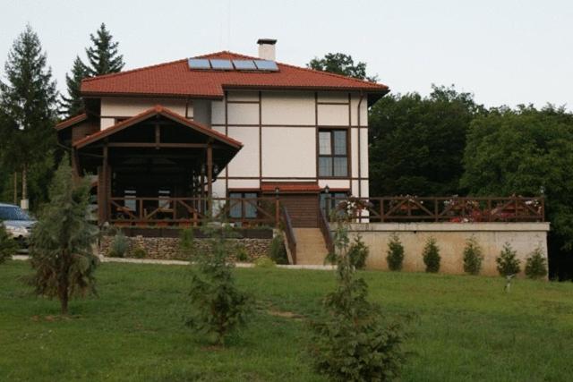 une grande maison avec un toit rouge dans un champ dans l'établissement Milkana Hotel, à Gabrovo
