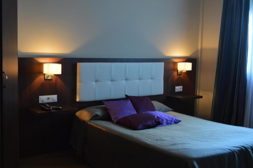 a bedroom with a bed with two purple pillows at Hotel Peña Cruz in Malpartida de Cáceres