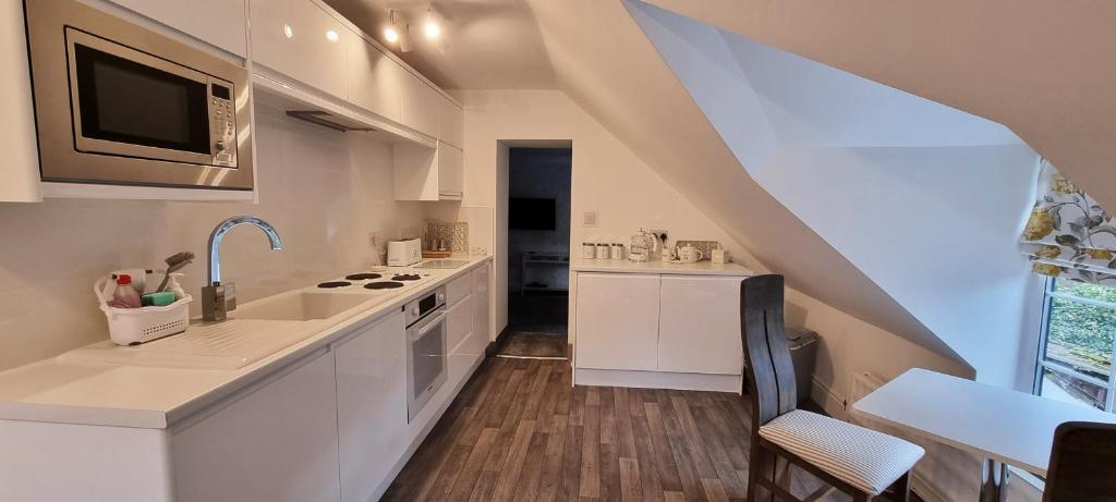 cocina blanca con fregadero y fogones en Modern and spacious 2 bedroom apartment with free parking, en Llansantffraid Glyn Ceiriog