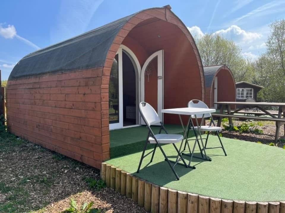 een kleine rode bakstenen schuur met een tafel en stoelen bij Blackbrook lodge Camping pods in Belper