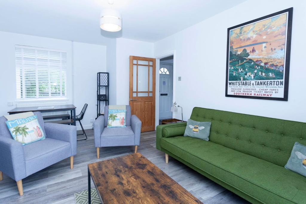 a living room with a green couch and two chairs at Magnolia cove in Whitstable