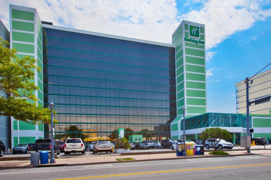 a large glass building with cars parked in a parking lot at Holiday Inn Va Beach-Oceanside 21st St, an IHG Hotel in Virginia Beach