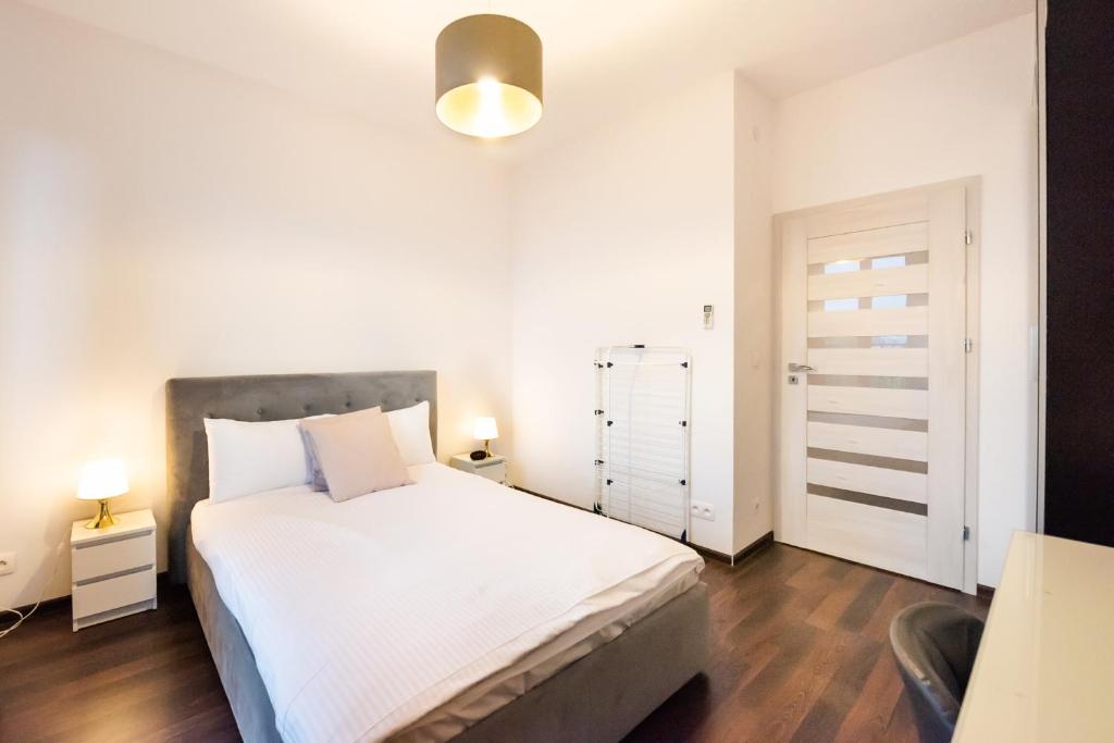 um quarto com uma grande cama branca e um candeeiro em Magazynowa Contemporary Apartment em Varsóvia
