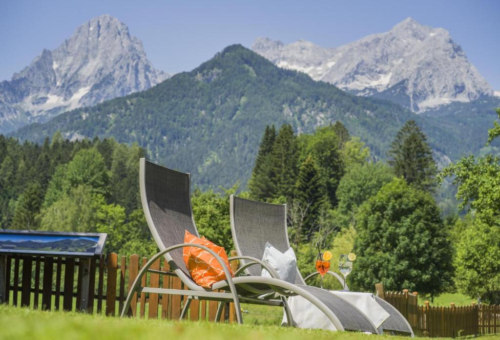 two chairs sitting in the grass with mountains in the background at Landhotel Gressenbauer in Hinterstoder