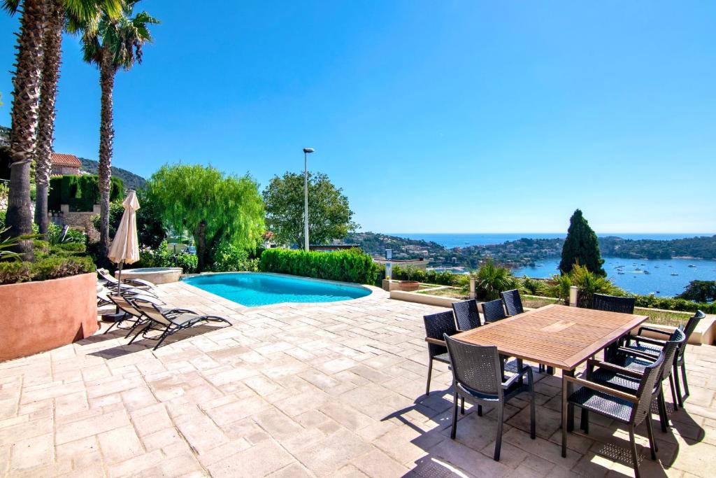 Un patio con mesa y sillas y una piscina. en Villa Soleil d'Or, en Villefranche-sur-Mer