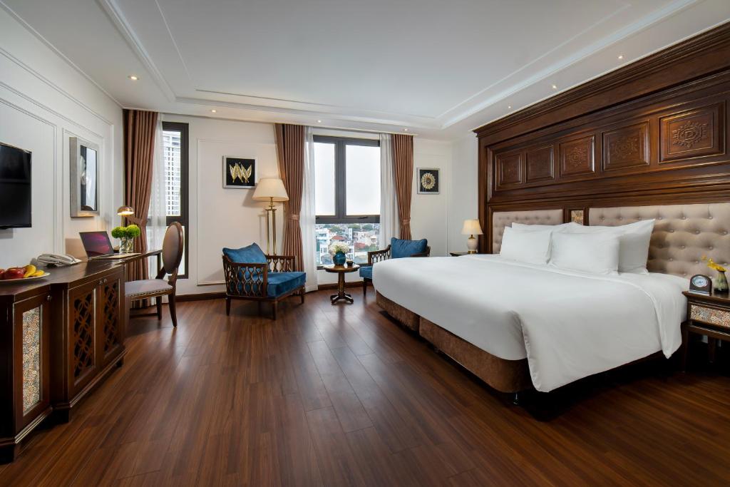 una camera d'albergo con un grande letto e una scrivania di The Q Hotel a Hanoi