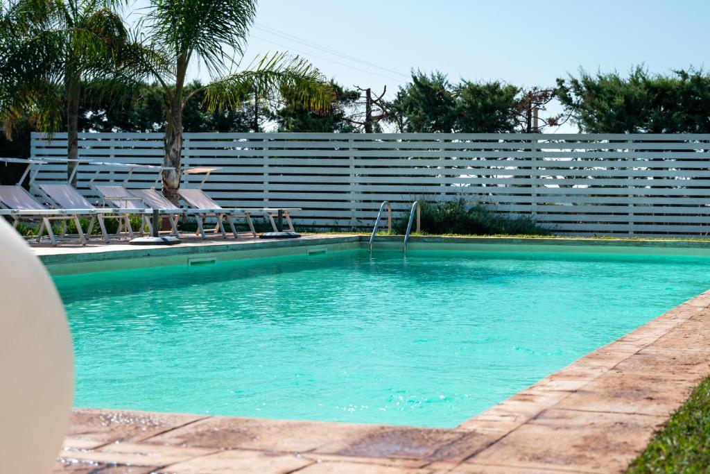 uma piscina com espreguiçadeiras e um campo de voleibol em Villa Savarino em Vittoria