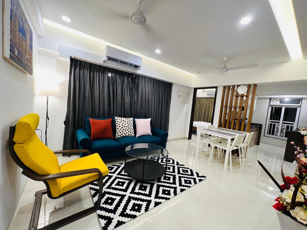 a living room with yellow chairs and a blue couch at 2BR Mumbai theme service apartment for staycation by FLORA STAYS in Mumbai