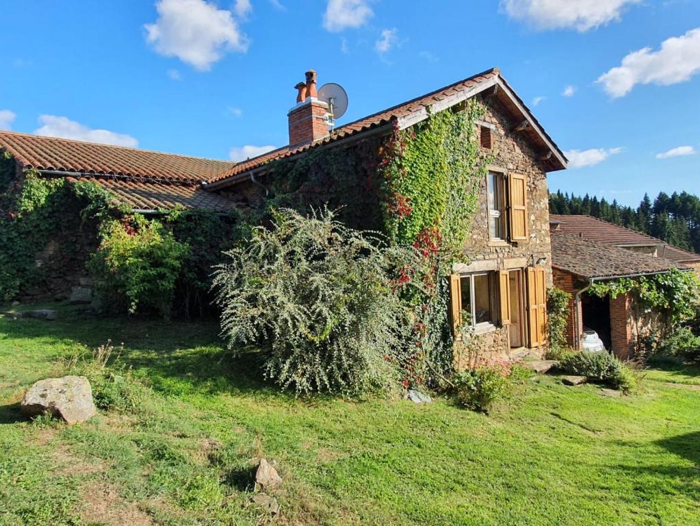 una casa con edera che cresce su un lato di essa di Eco-gîte panoramique face aux volcans avec ateliers couture bohème en option a Champagnac-le-Vieux