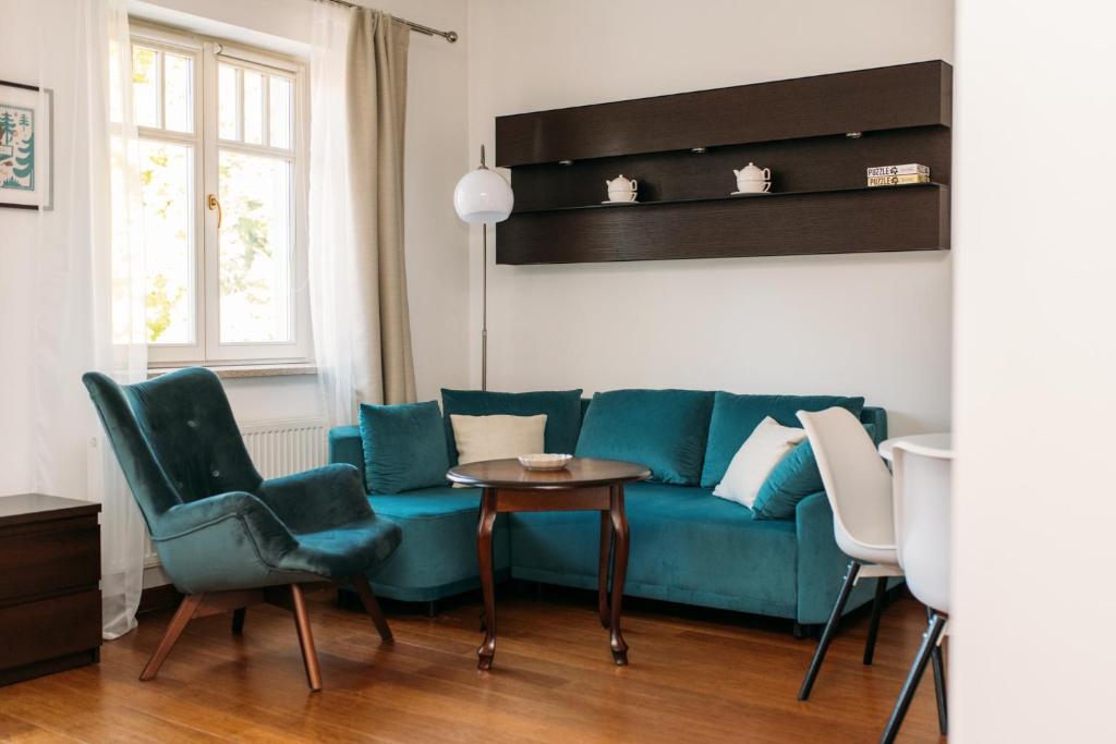 a living room with a blue couch and two chairs and a table at Apartament 19 Delux- Bliżej Zdroju in Polanica-Zdrój