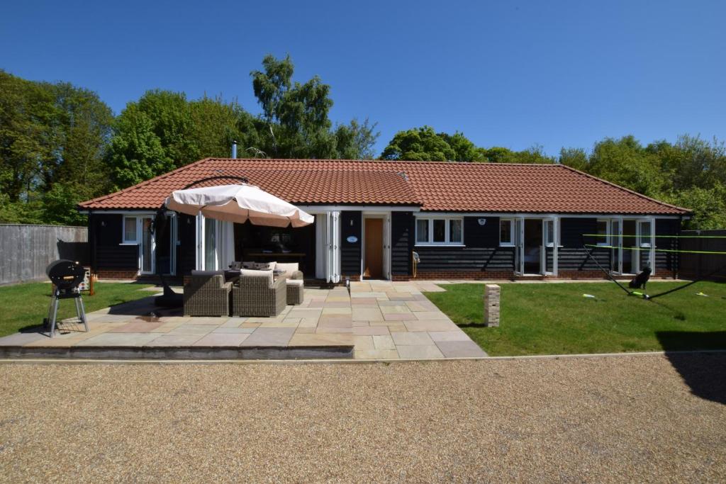 Casa con patio y sombrilla en Woodland Lodge, Aldeburgh, en Aldeburgh