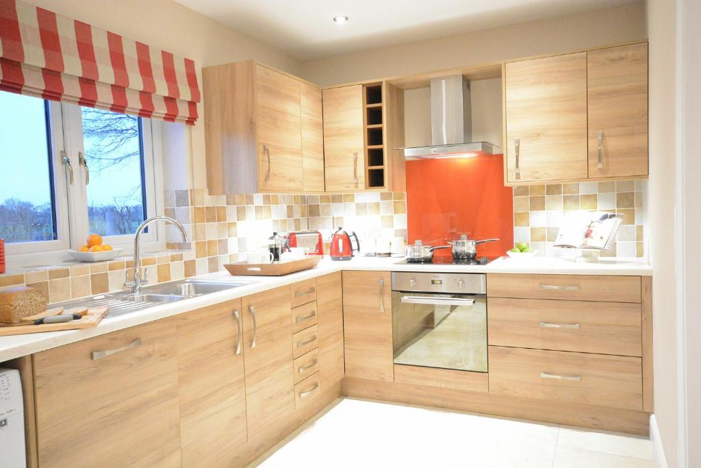 una cocina con armarios de madera y fregadero en Red Robin, Whepstead, en Whepstead