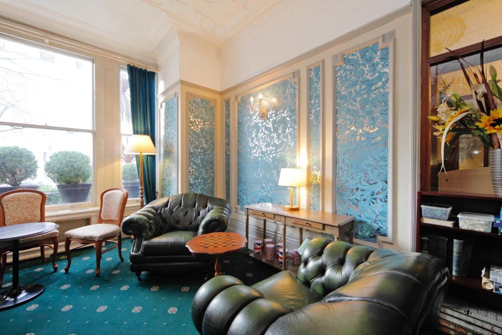a living room with leather furniture and blue wallpaper at London Visitors Hotel in London