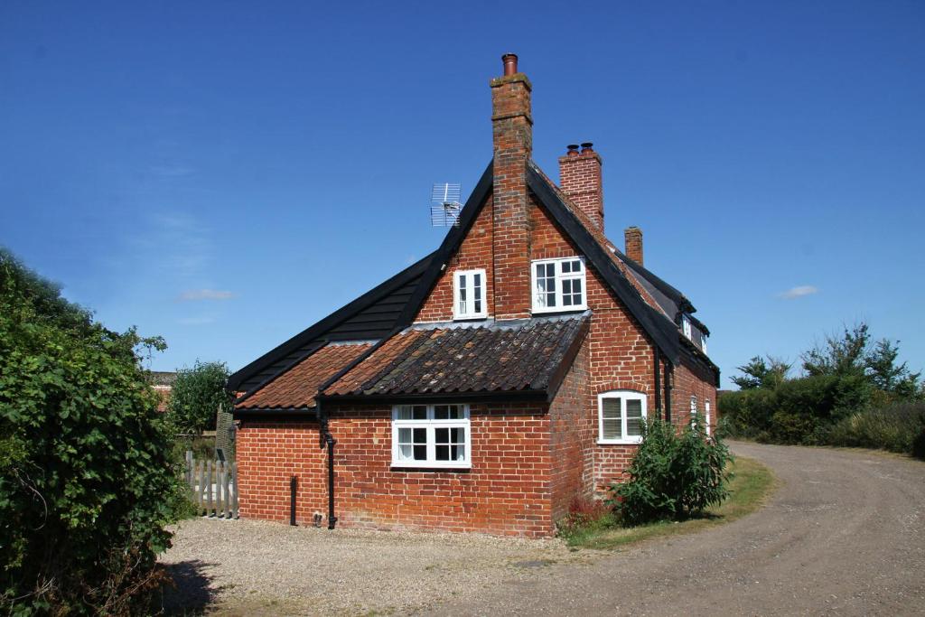 a small red brick house with a black roof at 1 Grange Cottages, Westleton in Westleton