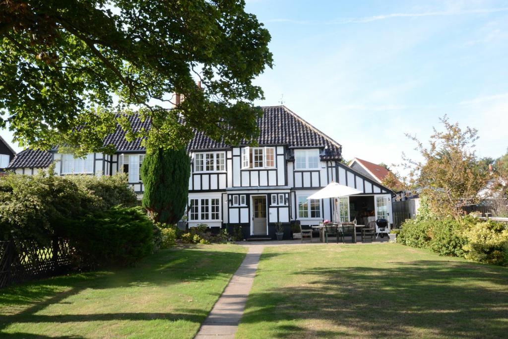 a large white and black house with a yard at 2 The Bays, Thorpeness in Thorpeness
