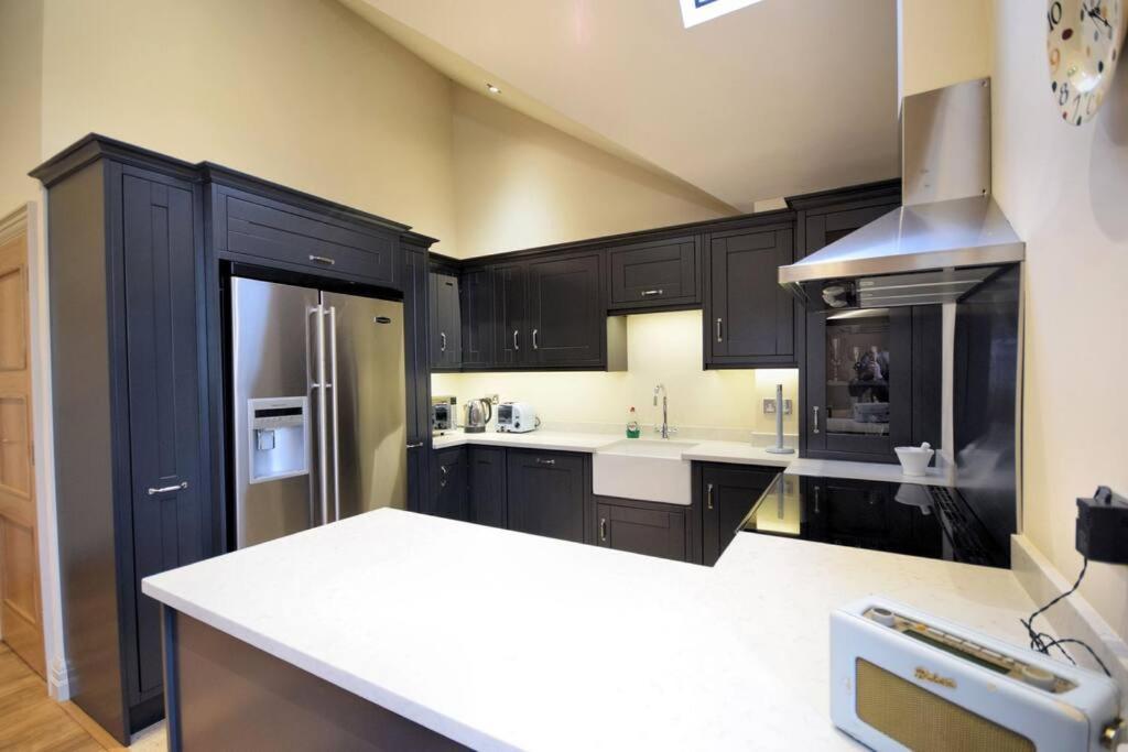 a kitchen with black cabinets and a white counter top at LOBSTER COTTAGE (Norfolk Costal Cottage) in Langham