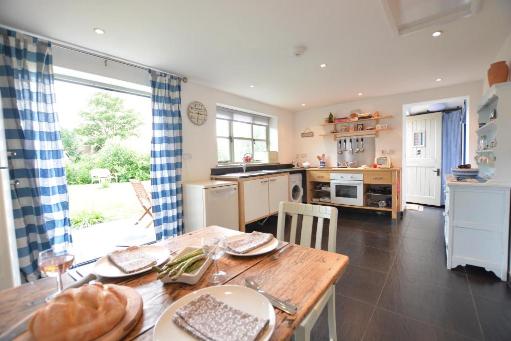 a kitchen with a wooden table and a dining room at Pudding Cottage, Westleton in Westleton