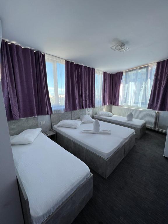 a hotel room with three beds and purple curtains at Hotel AMA WORLD in Constanţa