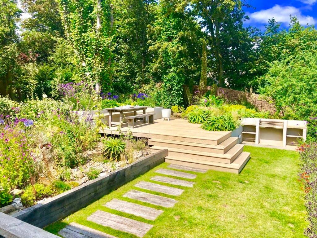 a garden with a wooden deck and benches at Aldeburgh Lodge Gardens in Aldeburgh